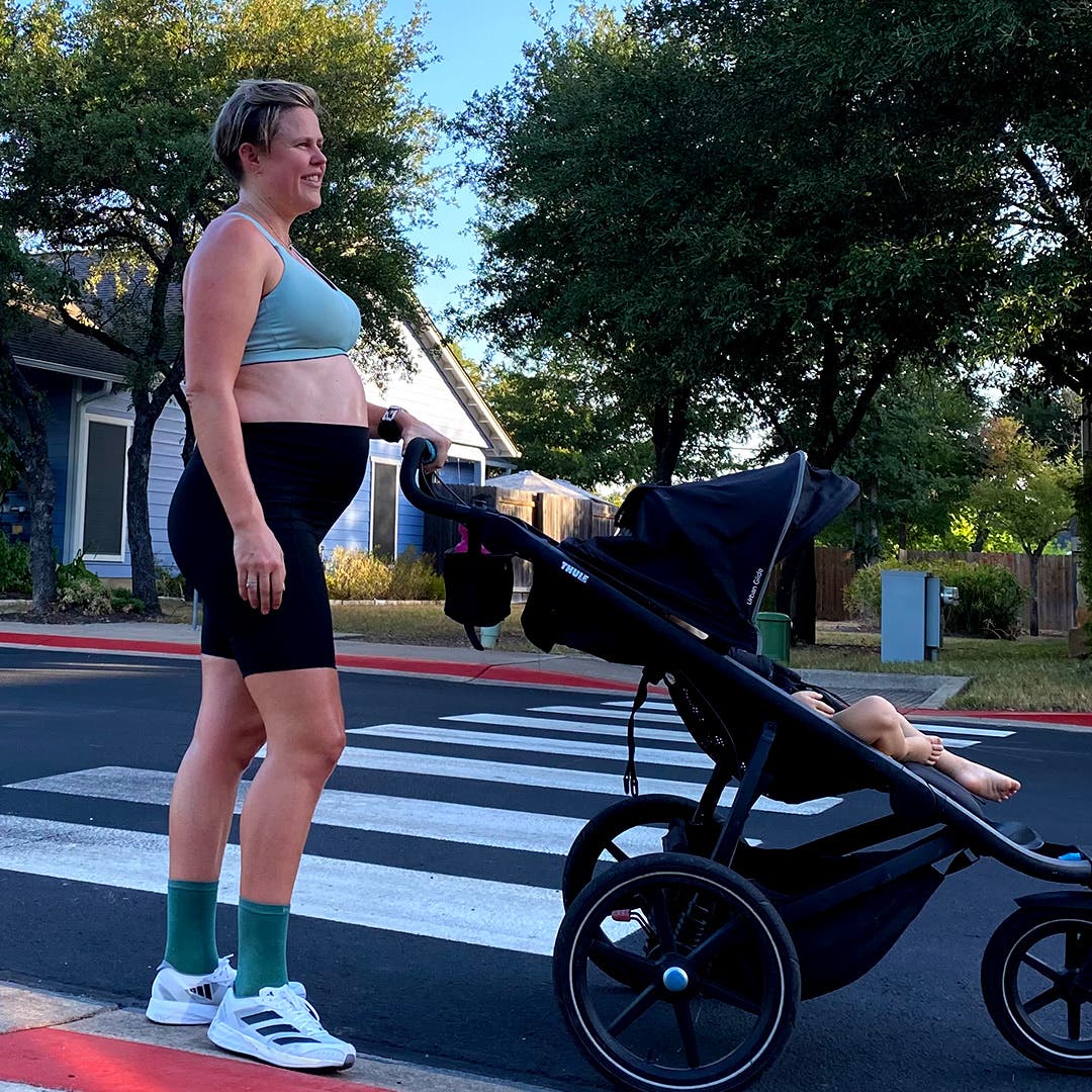 Cate Barrett pregnant with her second child on a walk pushing her first child in a stroller.