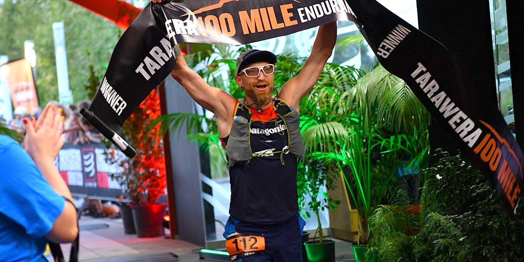 Jeff Browning finishing the course and holding a finish line ribbon in his hands