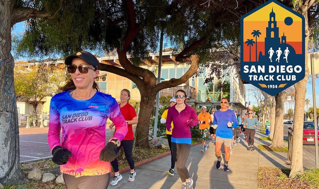 A group of San Diego Track Club runners running on a tree lined side walk. 