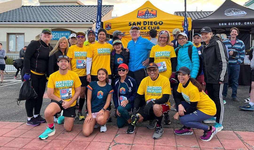 A group of San Diego Track Club runners sporting their club name on yellow tee shirts.