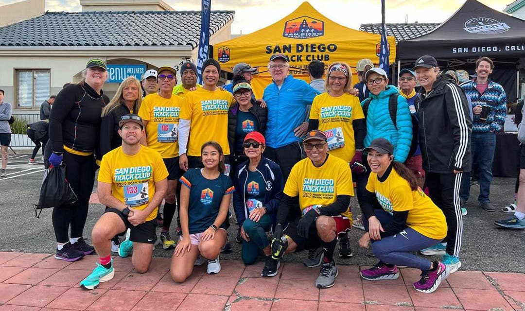 A group of San Diego Track Club runners sporting their club name on yellow tee shirts. 