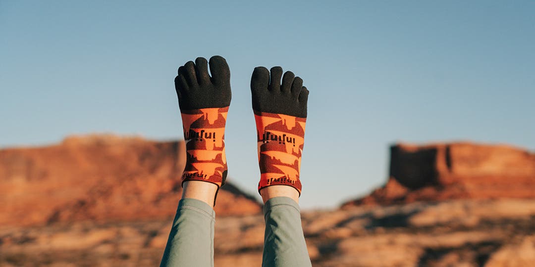 Artist Kika MacFarlane's legs up in the air wearing Injinji's Artist Designed Men's No-Show toesocks in Horizon.