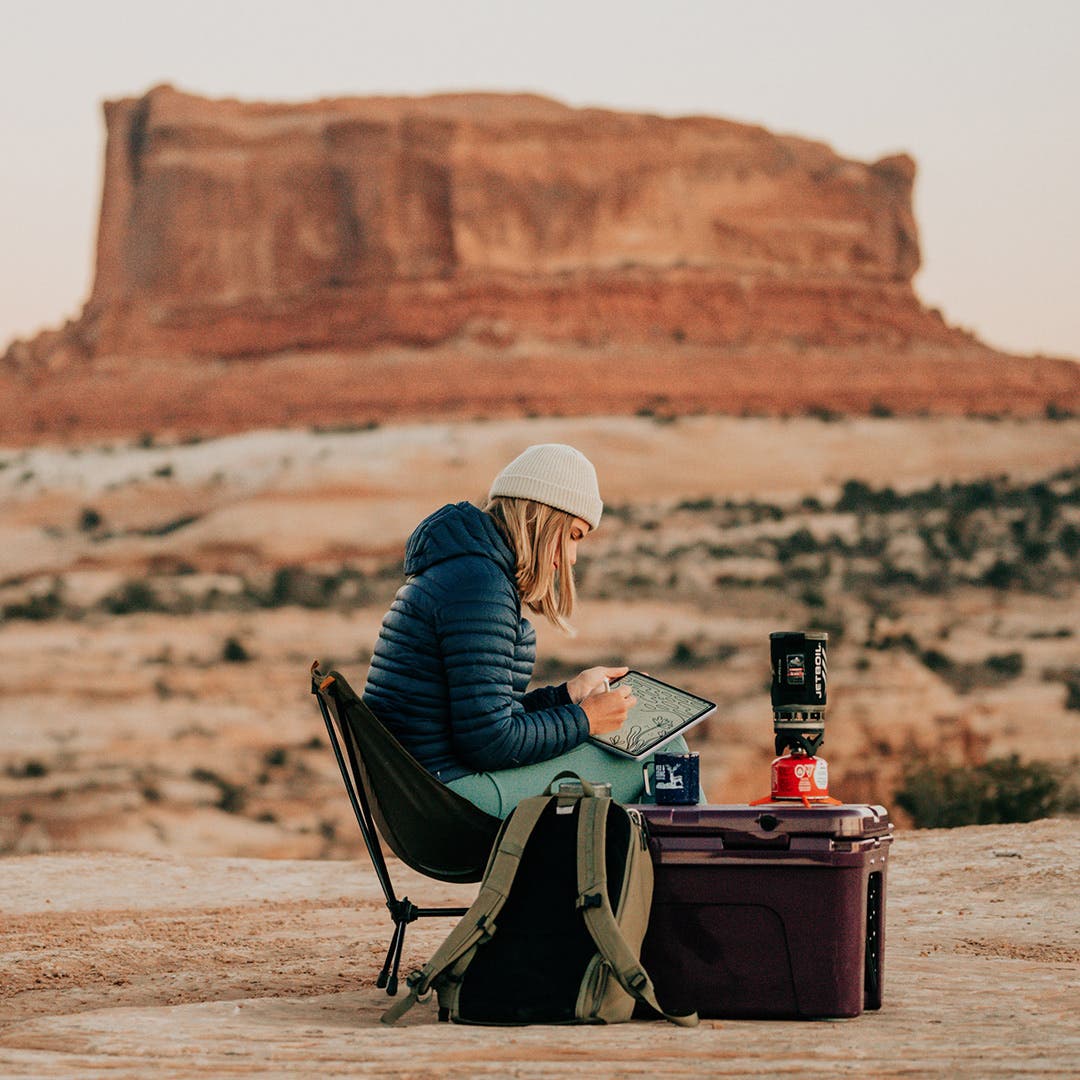 Artist Designed Canyons Collection artist Kika MacFarlane drawing at her camping spot in the desert of Moab, Utah.  
