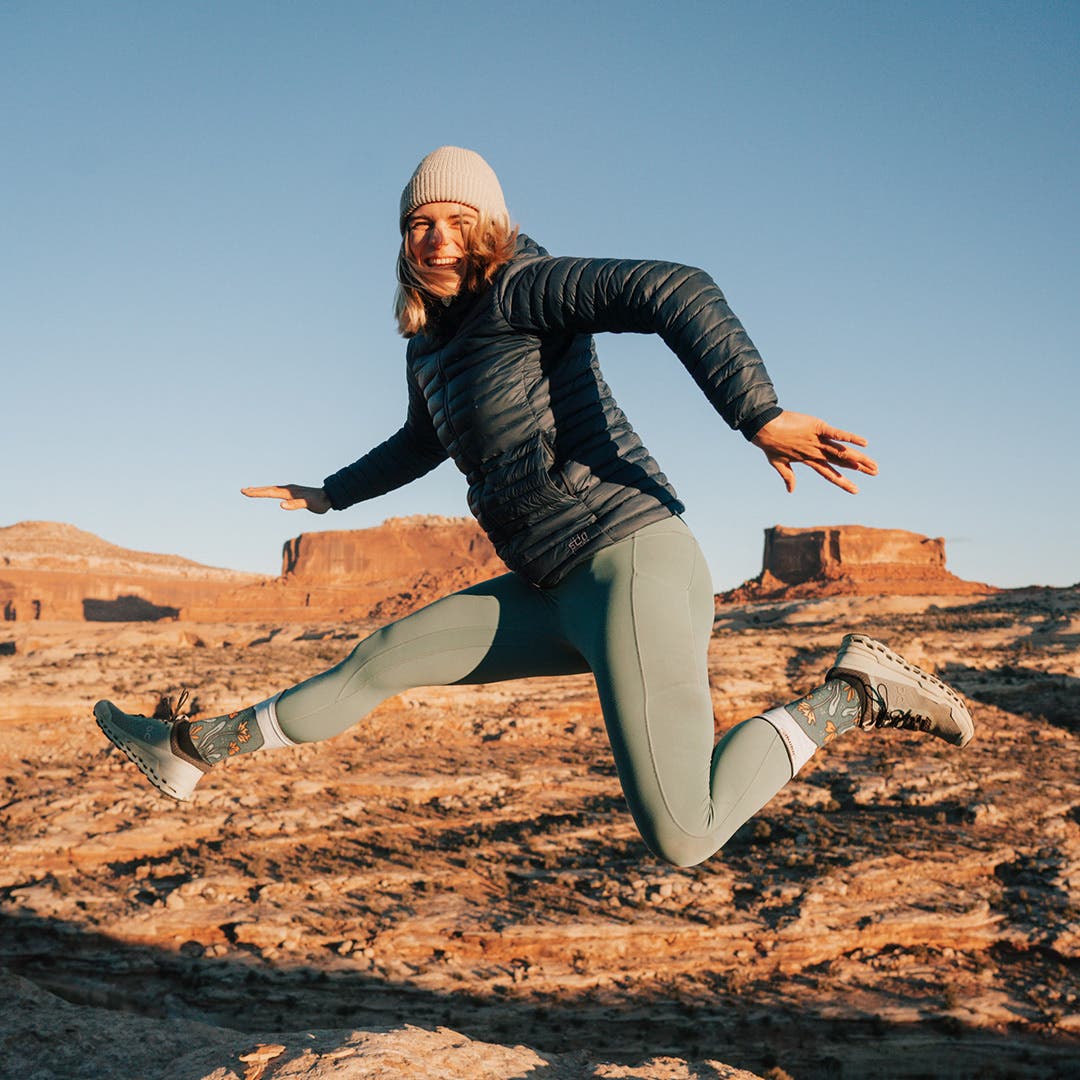 Kika MacFarlane, artist behind Injinji first Artist Designed series The Canyons collection, smiling and laughing mid jump.