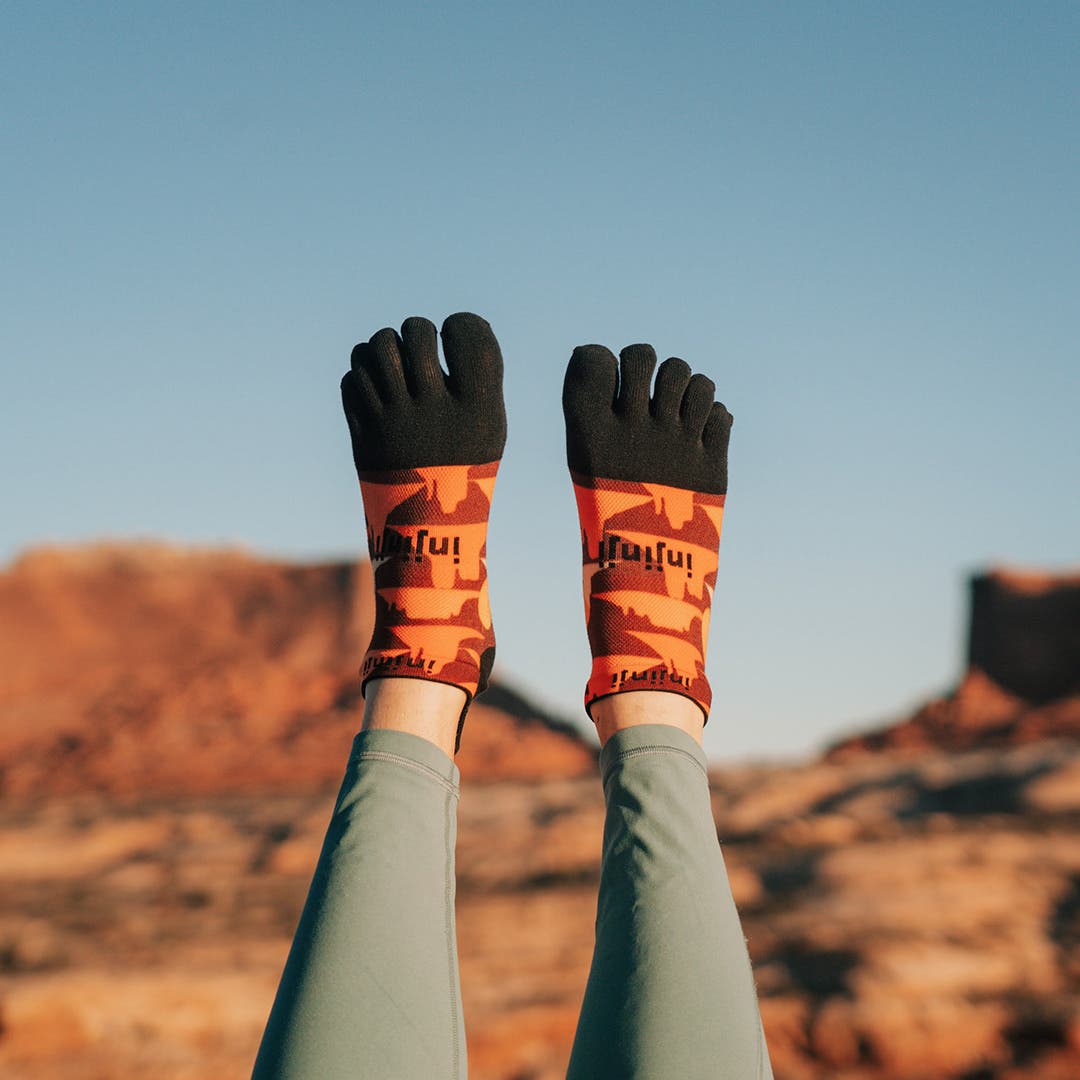 Artist Kika MacFarlane's legs up in the air wearing Injinji's Artist Designed Men's No-Show toesocks in Horizon.