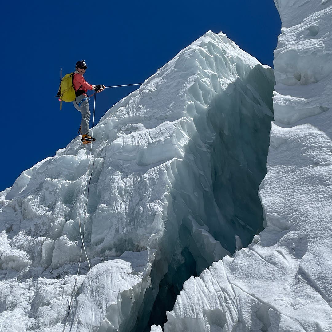Team Injinji Athlete Meghan Buchanan rappelling a glacier at the top of a mountain.