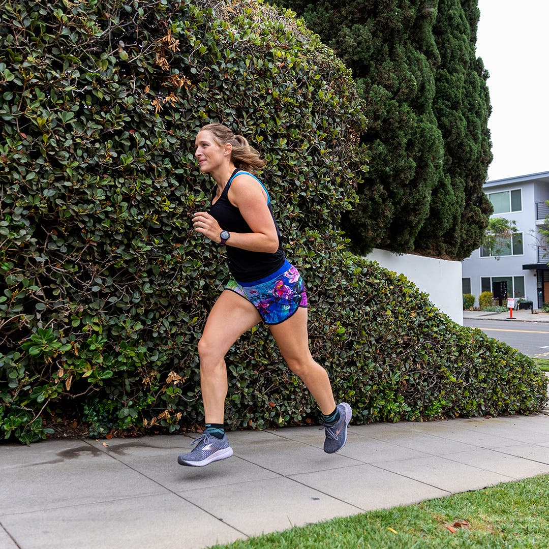 A woman running on a sidewalk in a suburban area.