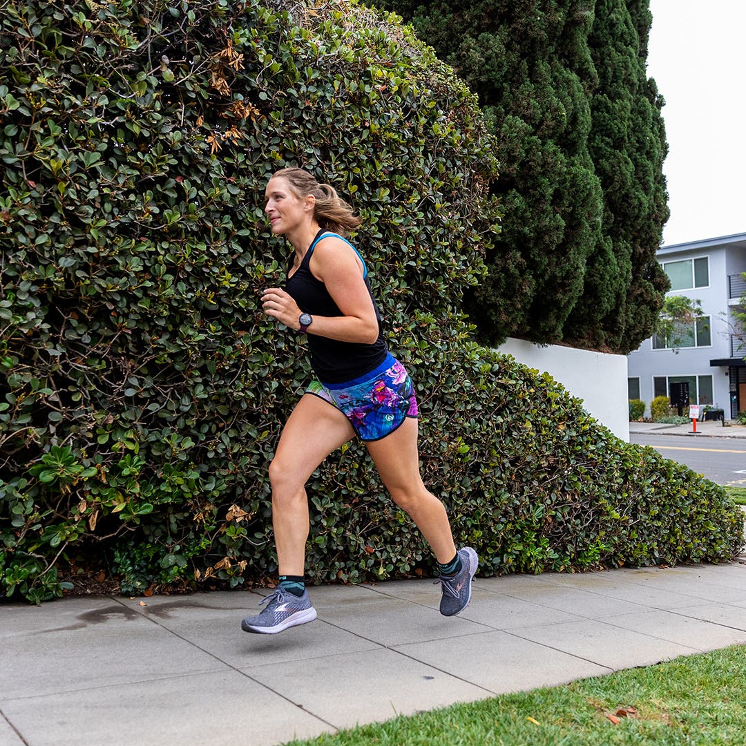 A woman running on a sidewalk in a suburban area. 