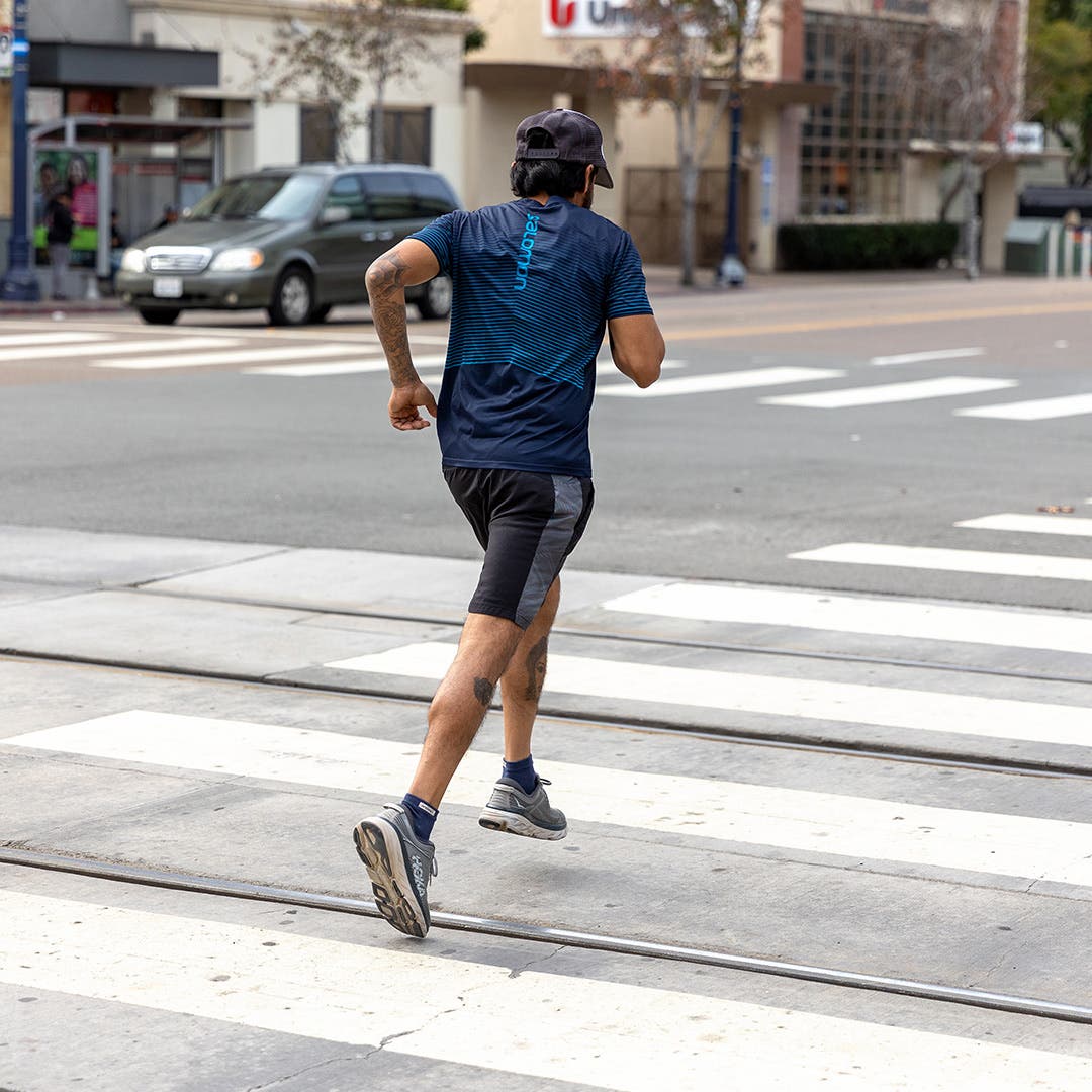 A man running through a cross walk in a metro area. 