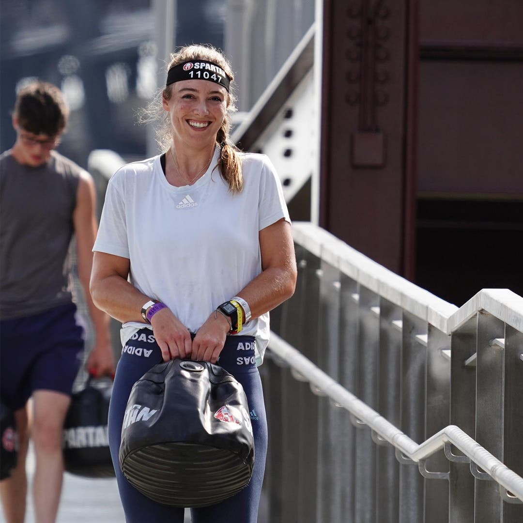 Alexandra Mueller carrying a weighted bag during an obstacle course race.