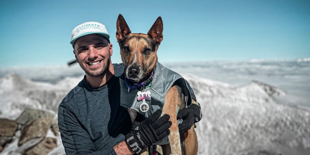 Team Injinji Athlete James Lauriello sitting at the top of mountain peak with his dog.