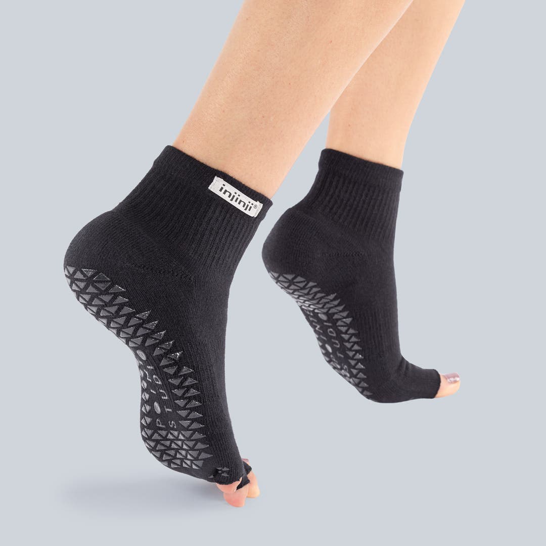 Closeup of someone standing on their toes wearing Injinji Grip Toeless Mini-Crew socks.