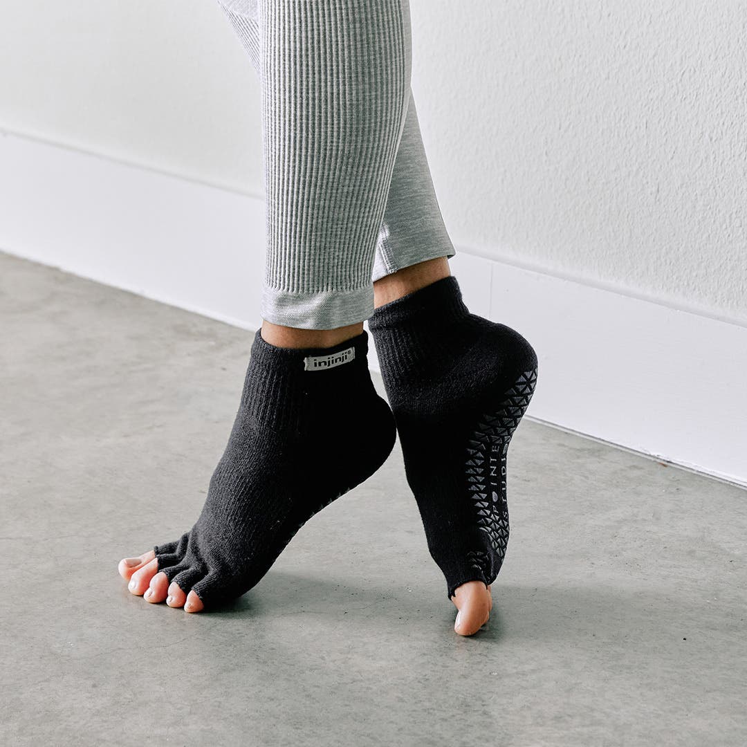 A person standing in a ballet position pointing their toes wearing Injinji Grip Toeless Mini-Crew socks.