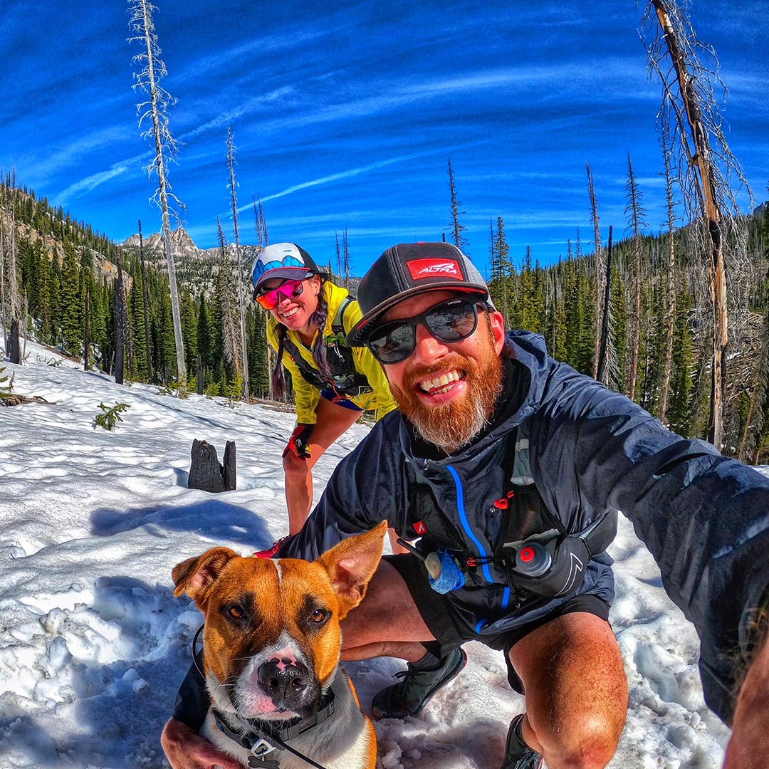 Trish and Garrick Arends with their dog Olly on a snow trail in the woods on a bluebird day.