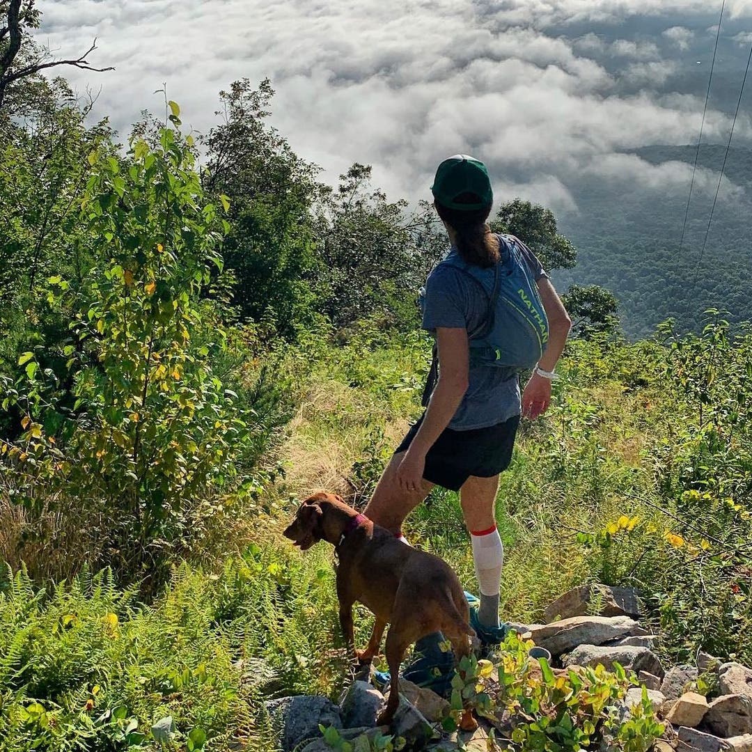 Mike Wardian gazing out beyond a mountain with his dog at his side.