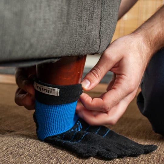 A man applying an old Injinji sock to the foot of a piece of furniture to protect the floors. 