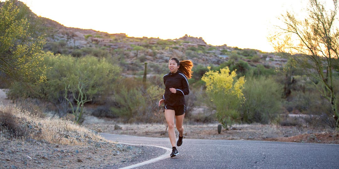 A woman running around a bend on a quiet country road.