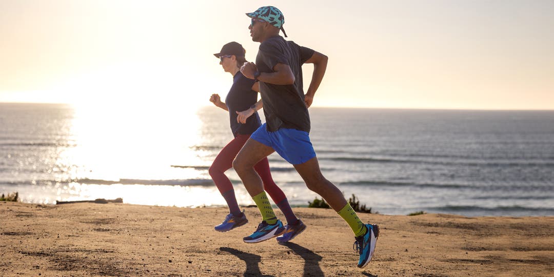 Two people running on a gravel trail by the beach.