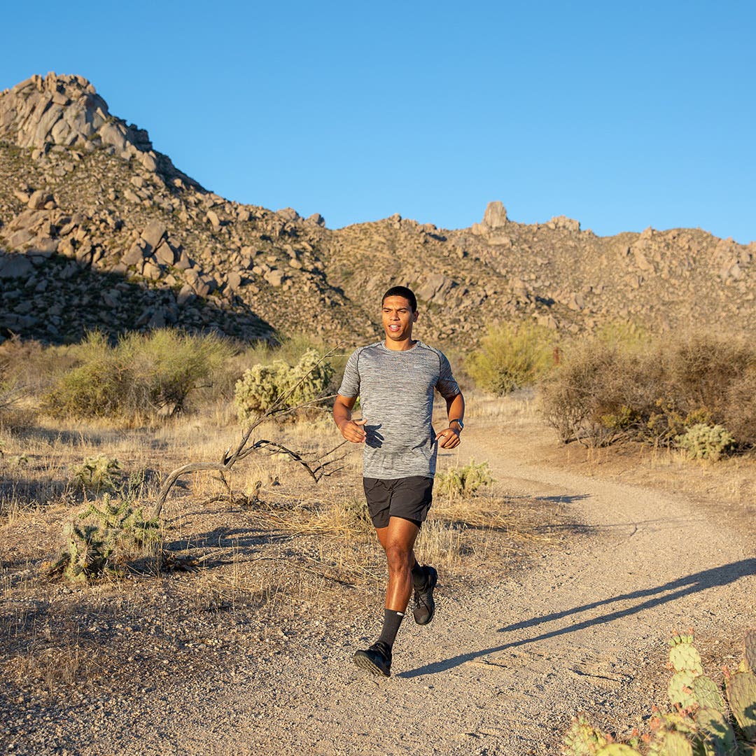A runner mid stride on a desert trail. 