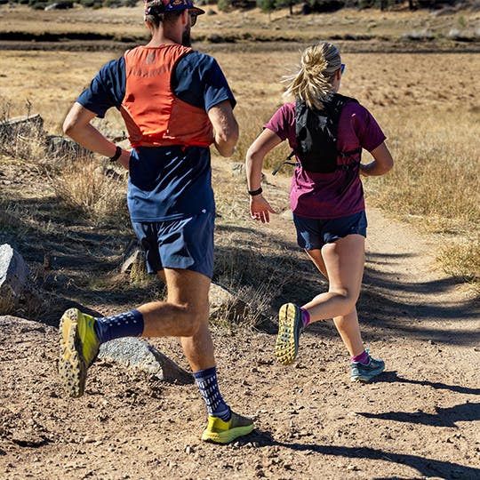 A man and woman trail running while wearing Injinji trail crew toesocks. 