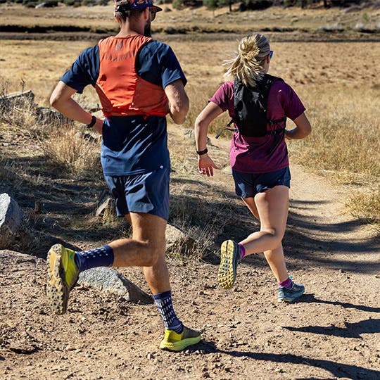 A man and woman trail running while wearing Injinji trail crew toesocks. A man and woman trail running while wearing Injinji trail crew toesocks.