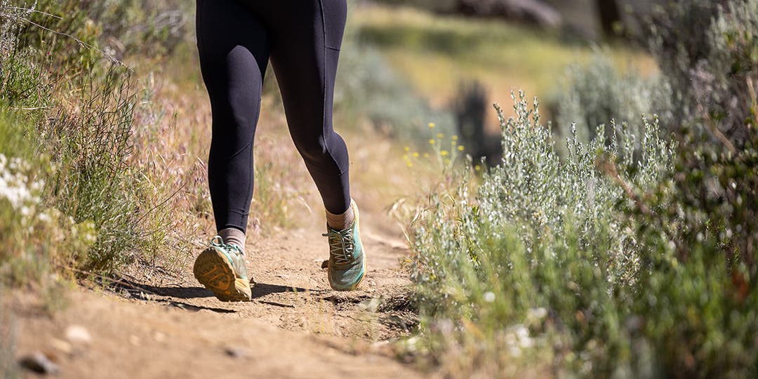 A woman running on a dirt trail.