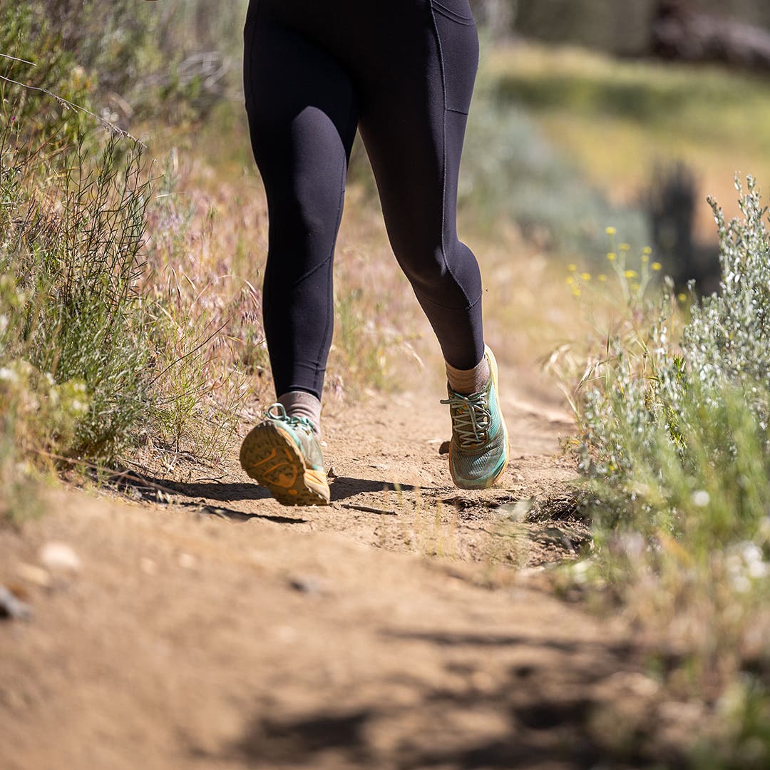A woman running on a dirt trail. 