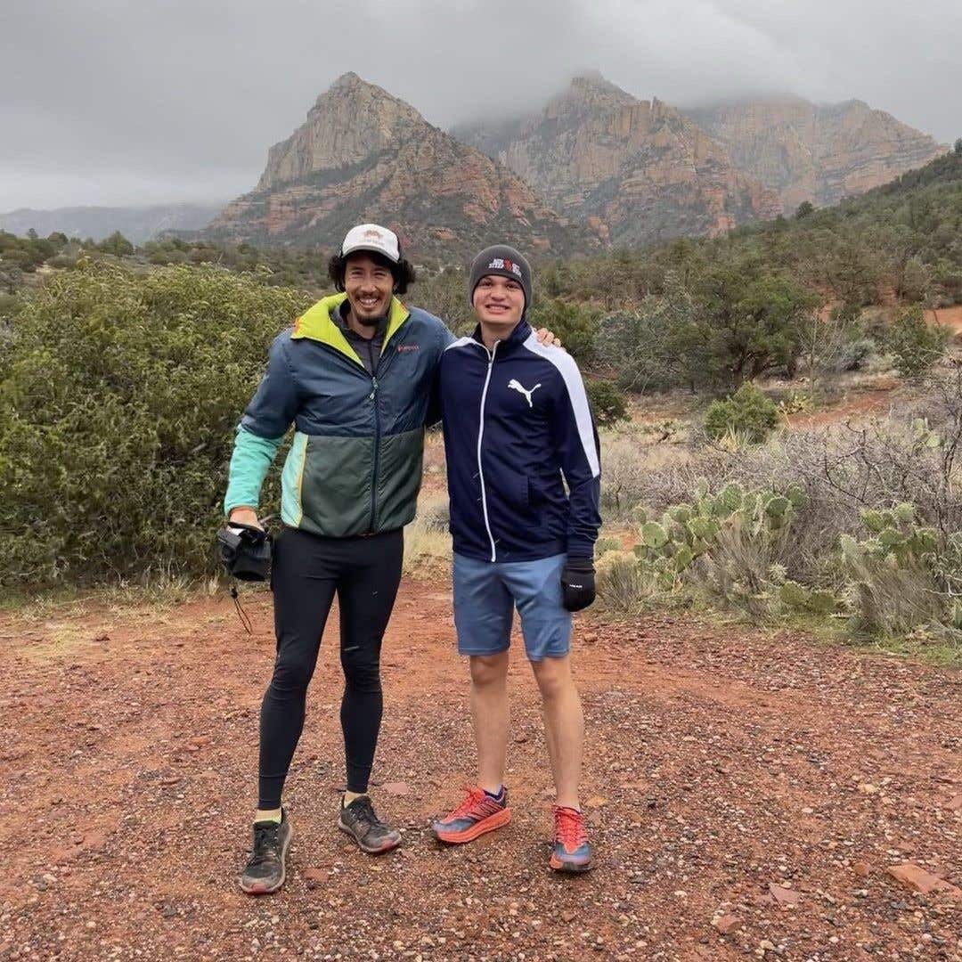 Team Injinji athlete Zachary Bates standing with his running coach Nickademus De La Rosa out on a trail.