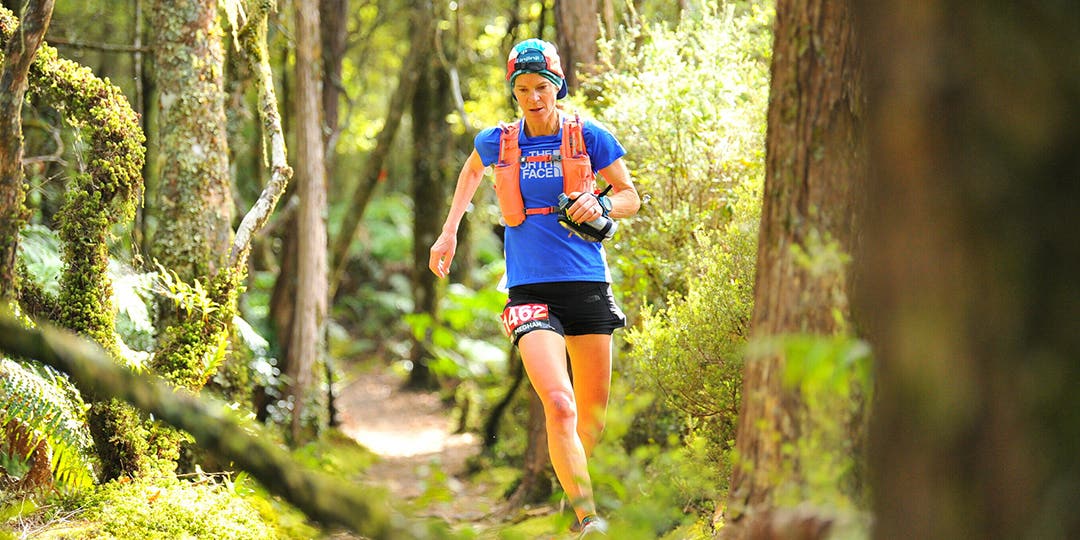 Meghan Canfield running in the green forest in a sunny weather