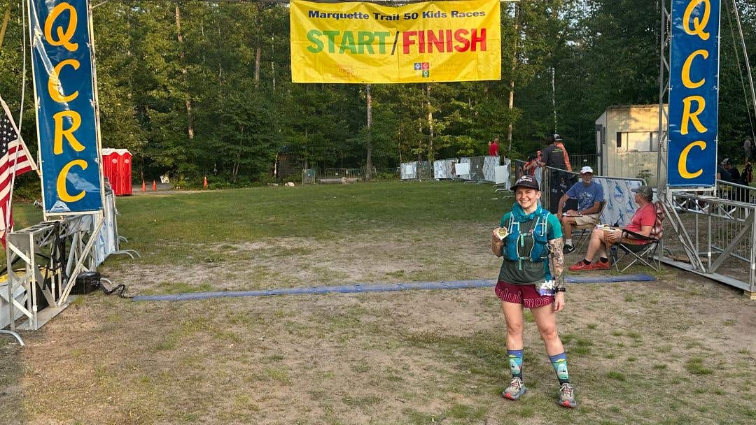 Team Injinji athlete Jessica Storrison-Carmean standing at the finish line of the Marquette Trail race.