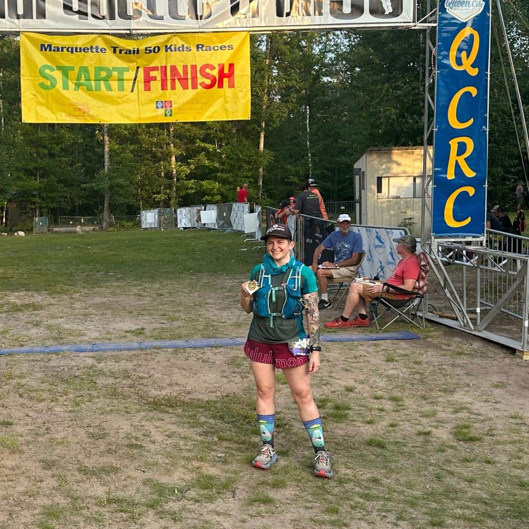 Team Injinji athlete Jessica Storrison-Carmean standing at the finish line of the Marquette Trail race.