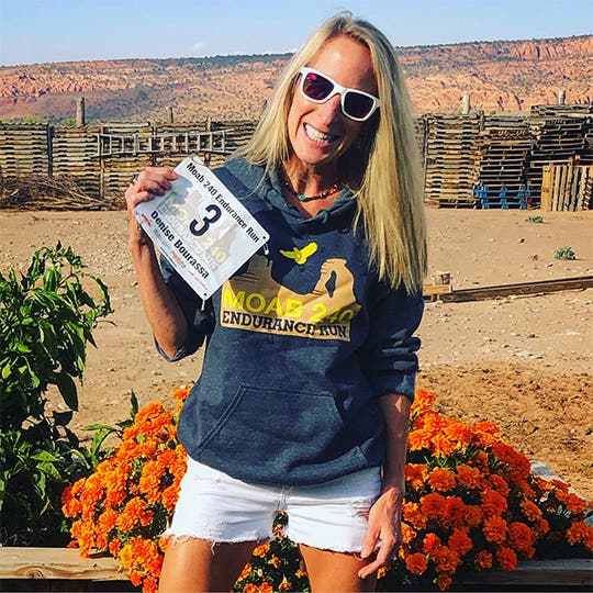 Denise Bourassa in the "MOAB 240 Endurance Run" hoodie holding her participant number in hand