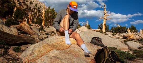 A Hiker pulling on their baselayer socks, the Injinji Liner Crew.