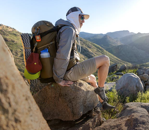 A backpacker taking a break on a boulder with their shoes off wearing Injinji Outdoor Midweight Crew Wool toesocks.