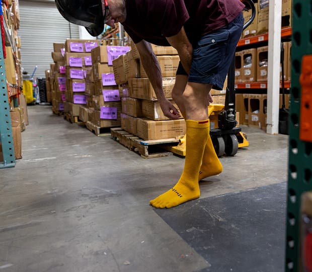 A person in a warehouse wearing the Injinji Boot Original Weight OTC