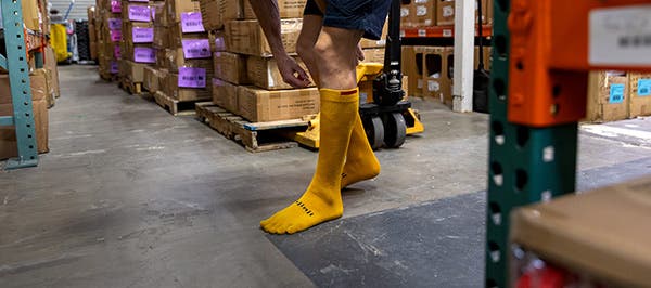 A person in a warehouse wearing the Injinji Boot Original Weight OTC