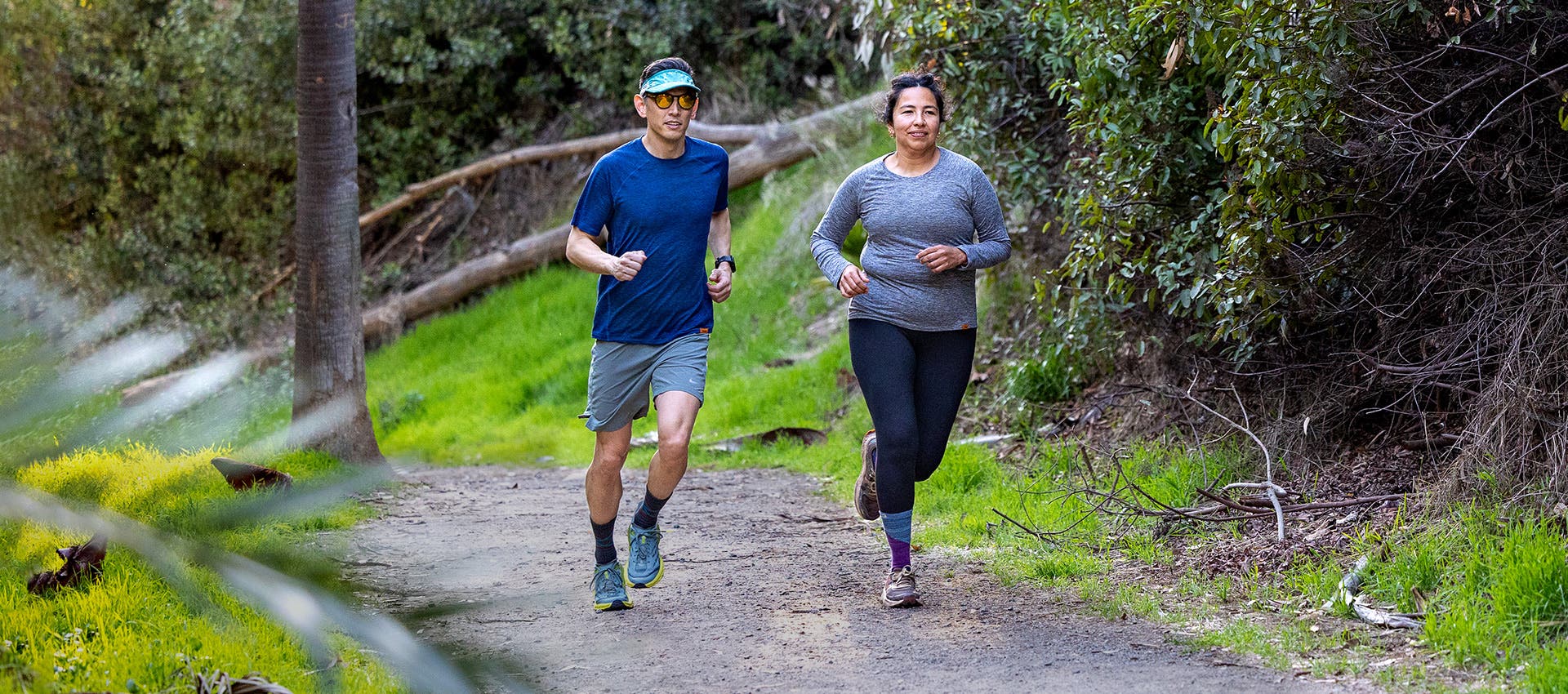 Two people wearing shirts from the new Injinji Performance Shirt Collection while running along a trail.