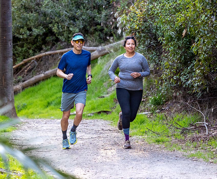 Two people wearing shirts from the new Injinji Performance Shirt Collection while running along a trail.