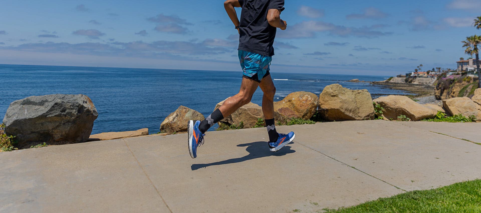 A runner training on a seaside path wearing Injinji Run Lightweight Crew running socks.