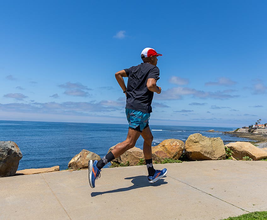 A runner training on a seaside path wearing Injinji Run Lightweight Crew running socks.
