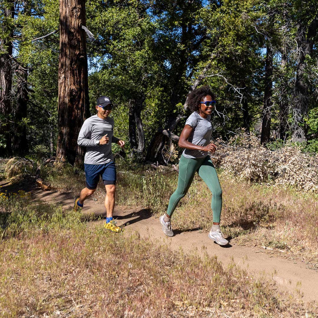 Two people trail running wearing the Trail Midweight Mini-Crew toesocks and the Women's Trail Midweight Mini-Crew toesocks. 