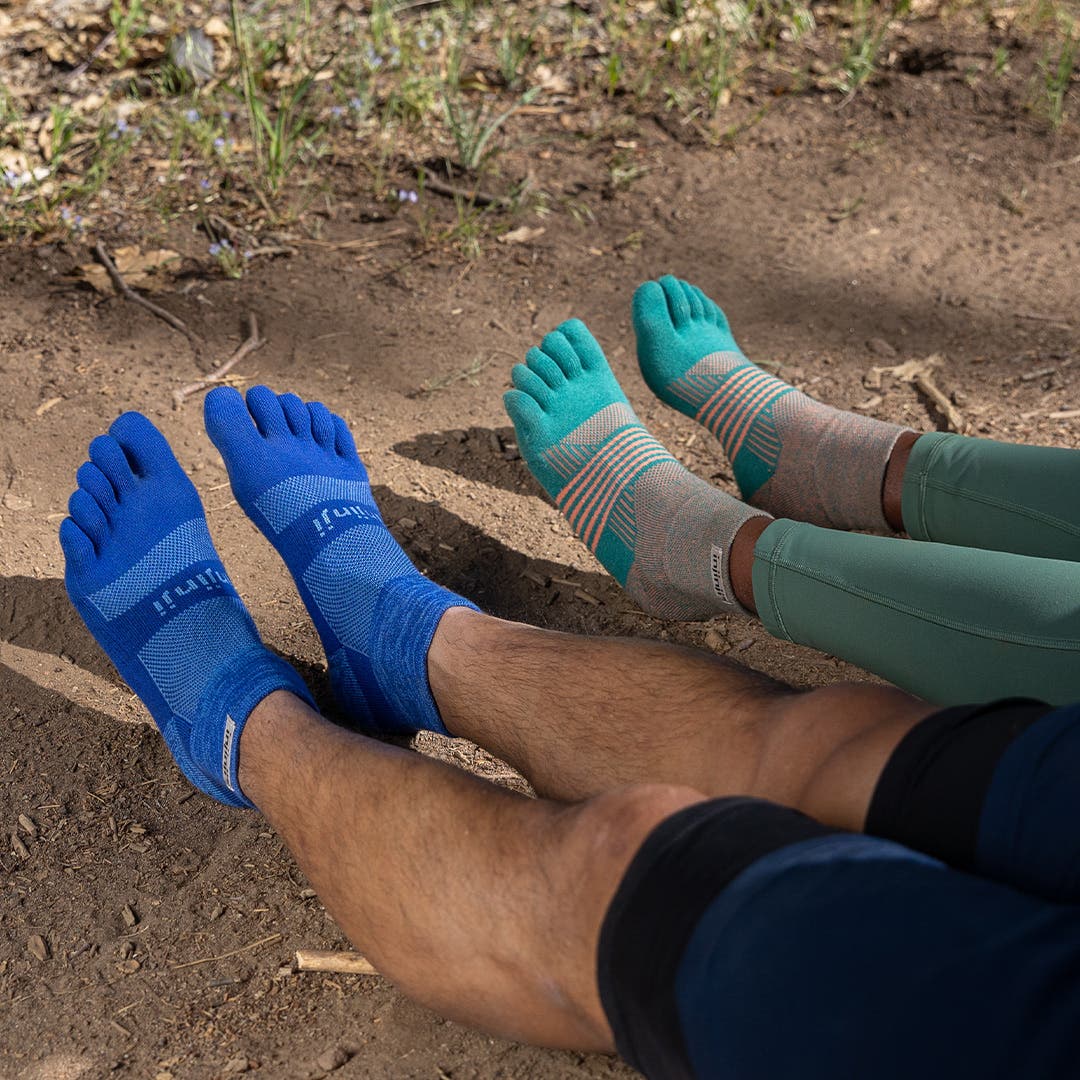 Two runners wearing the Trail Midweight Mini-Crew toesocks and the Women's Trail Midweight Mini-Crew toesocks. 