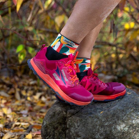 Closeup of someone's feet on top of a rock in the woods wearing Injinji Artist Designed Women's Mini-Crew and Altra running shoes.