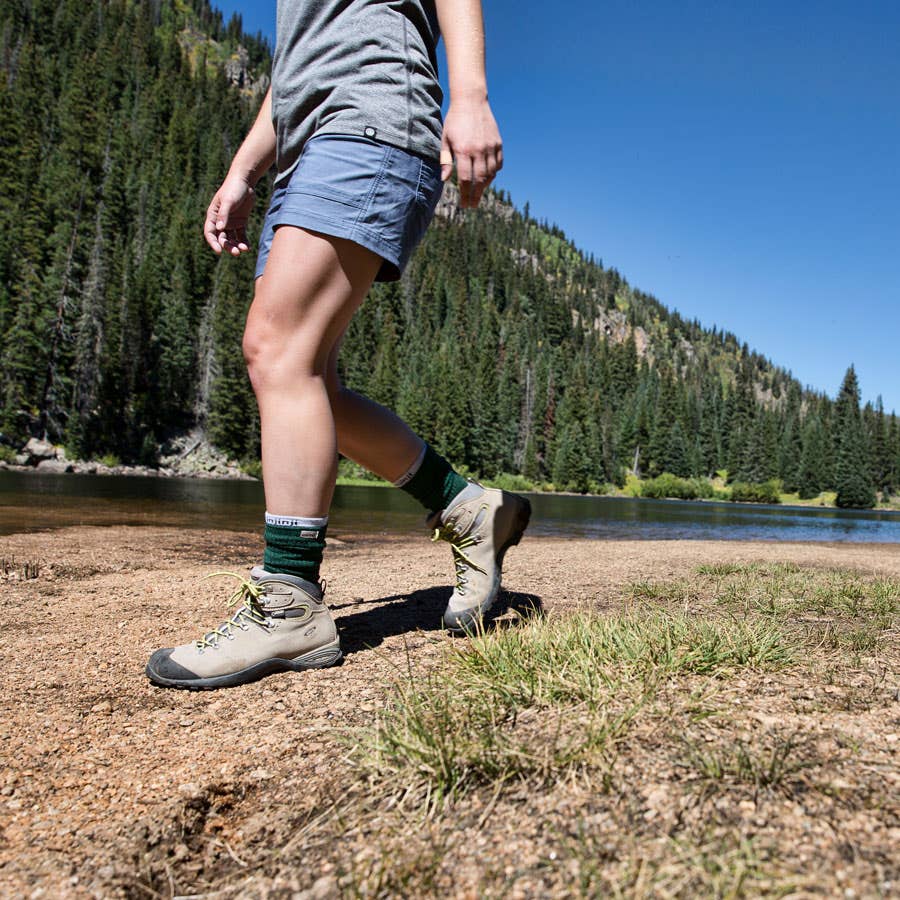 A backpacker hiking near an alpine lake with snowy mountains in the background. 