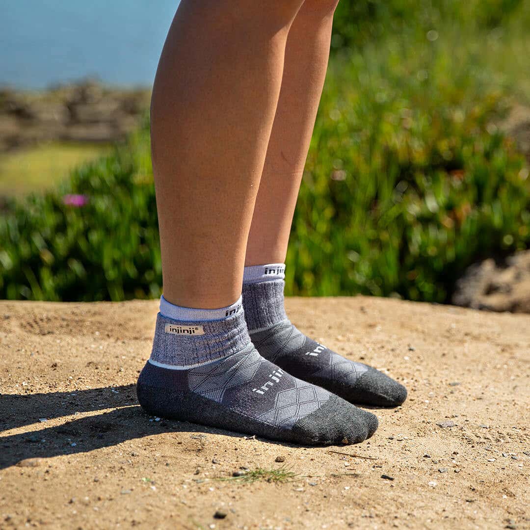 A person standing on top of a packed dirt mound wearing Injinji Liner + Runner socks. 