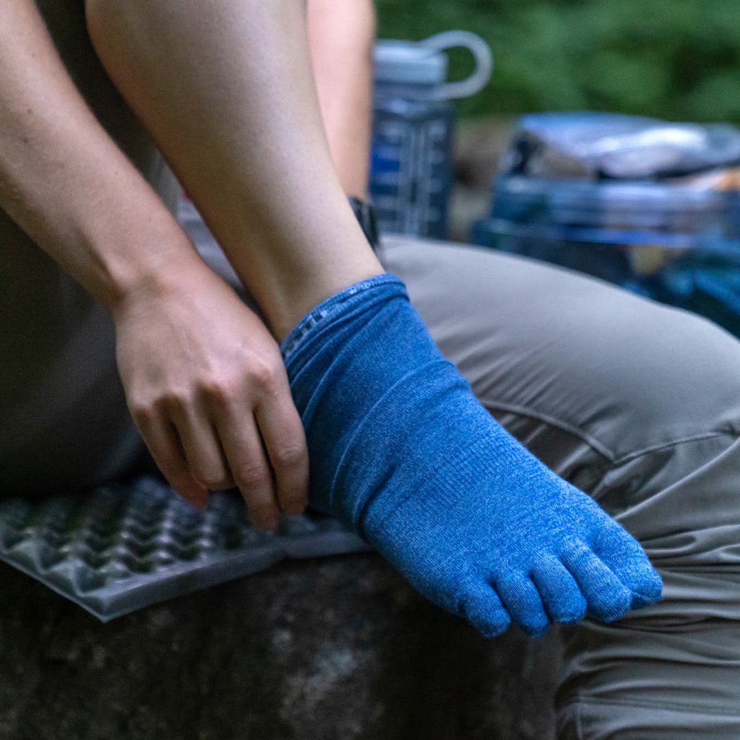 A hiker putting on the Liner Crew socks in dolomite. 